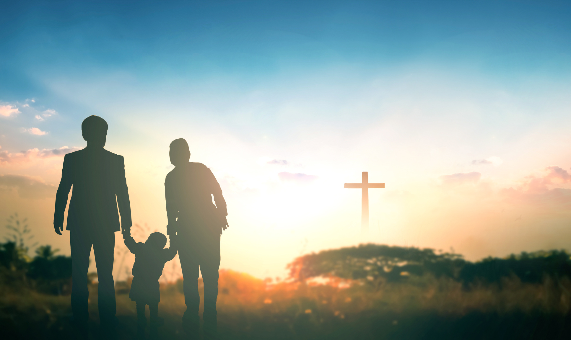 Family concept: Parents and children pray together on the cross background
